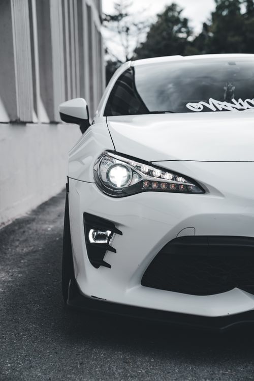 Free Close-up of a modern white sports car with sleek design parked on a city street. Stock Photo