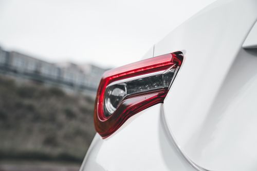 Free Detailed view of a sleek red tail light on a modern white car, highlighting automotive design craftsmanship. Stock Photo