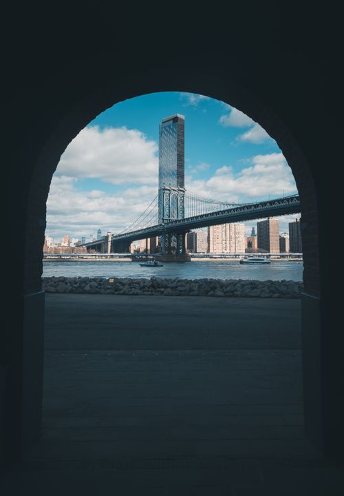 Free Dramatic view of Manhattan Bridge framed by an arch in New York City on a bright day. Stock Photo