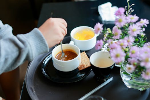 A relaxing breakfast setup with coffee, tea, and flowers on a tray.