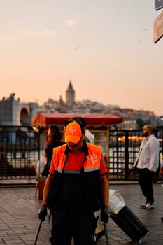 Street cleaner working at sunset in Istanbul with Galata Tower in the background. Urban scene with vibrant colors.