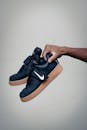 中性背景下，特写一只握着口香糖鞋底的时尚黑色运动鞋