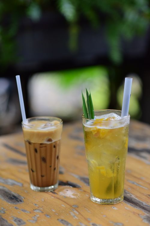 Free Two refreshing iced drinks with straws on a rustic wooden table outdoors. Stock Photo