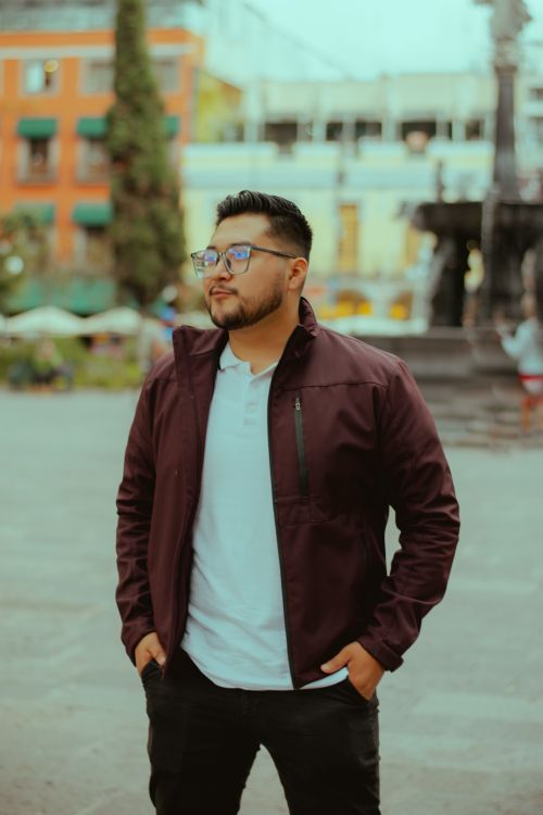 Free Casually dressed man standing confidently in a vibrant urban setting with historic architecture. Stock Photo