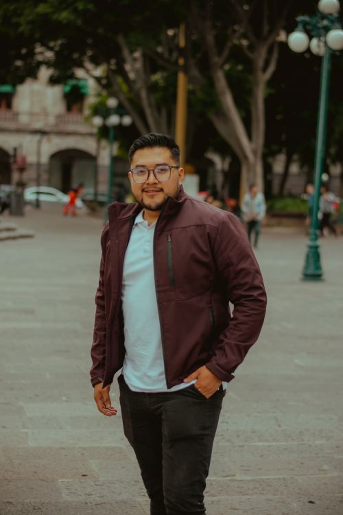 Free Man in casual attire posing confidently outdoors in a city square. Stock Photo