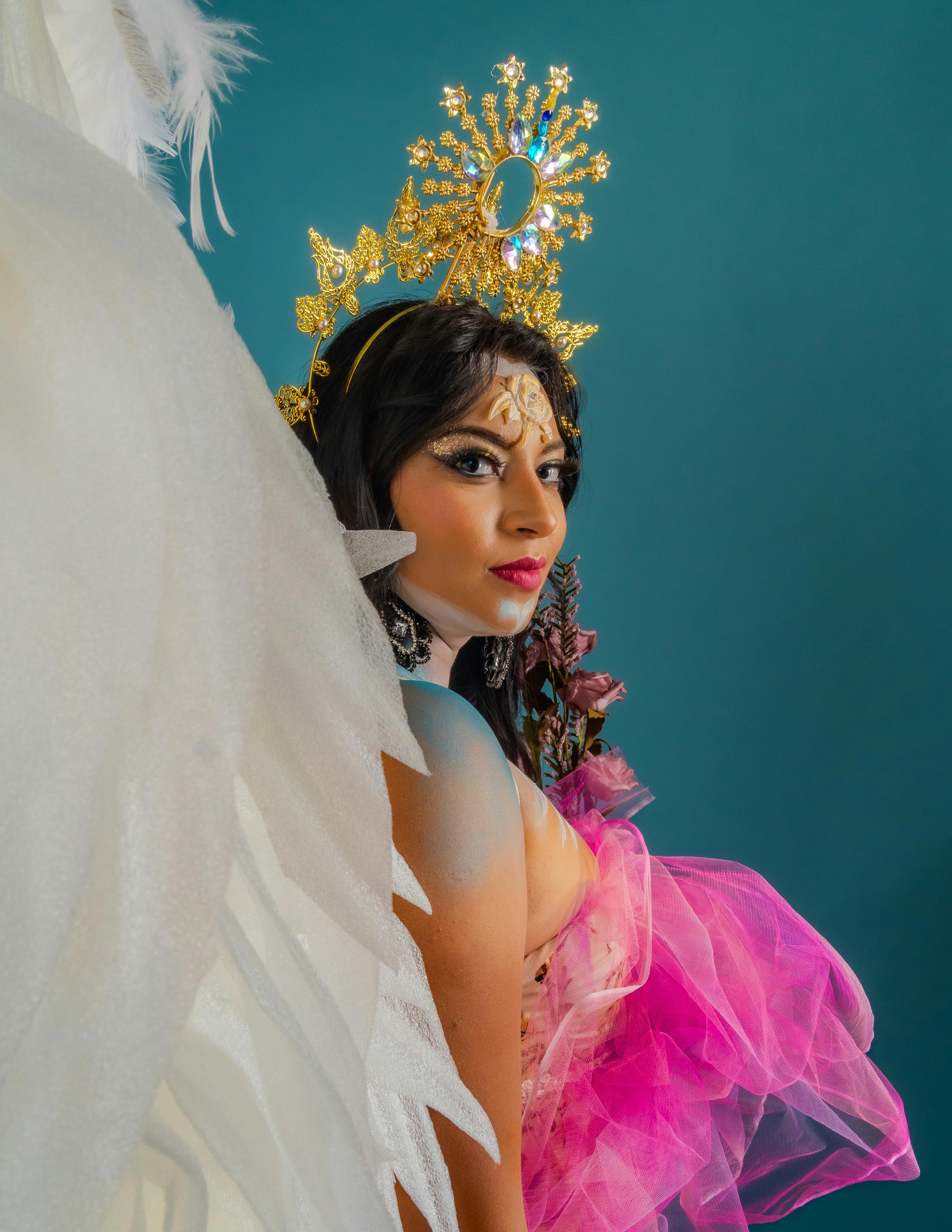 Portrait of a woman in elegant costume with angelic wings and golden crown, exuding grace.