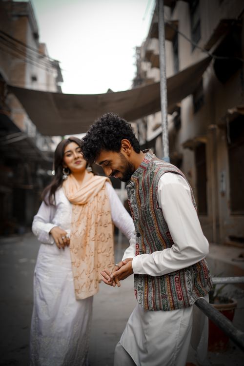 Free A joyful couple enjoying a stroll in traditional attire on an urban street. Perfect for cultural themes. Stock Photo