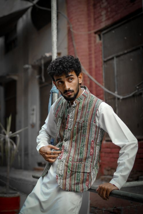 Free Stylish young adult man in traditional attire posing in a vibrant urban alley setting. Stock Photo