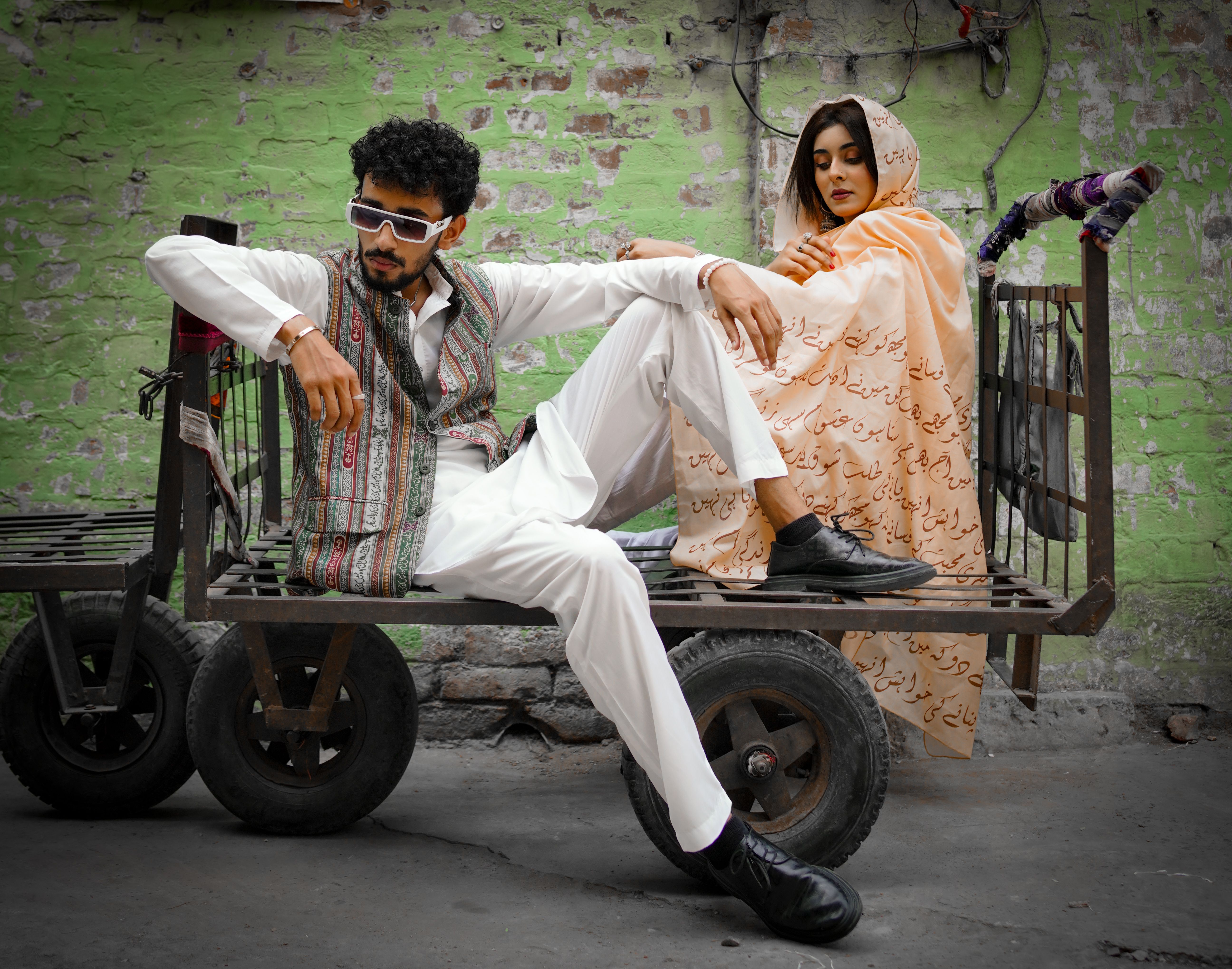 Fashionable young adults in stylish attire posing on a rustic cart against a vibrant urban backdrop.