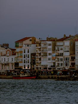 Charming seaside cityscape with apartment buildings by the water at sunset, creating a moody ambiance.