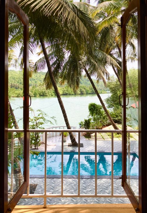 Free Inviting tropical poolside scene framed by palm trees with a serene river view. Stock Photo