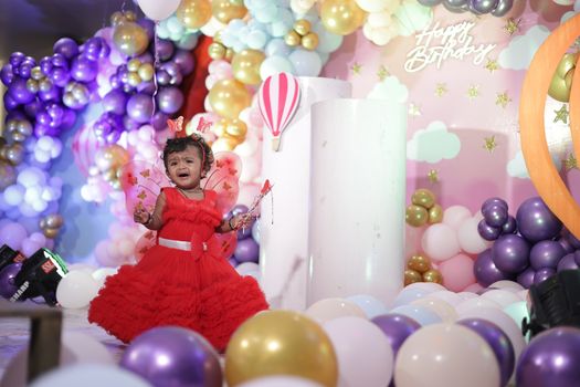 A joyful birthday celebration featuring a little girl dressed as a fairy surrounded by colorful balloons indoors