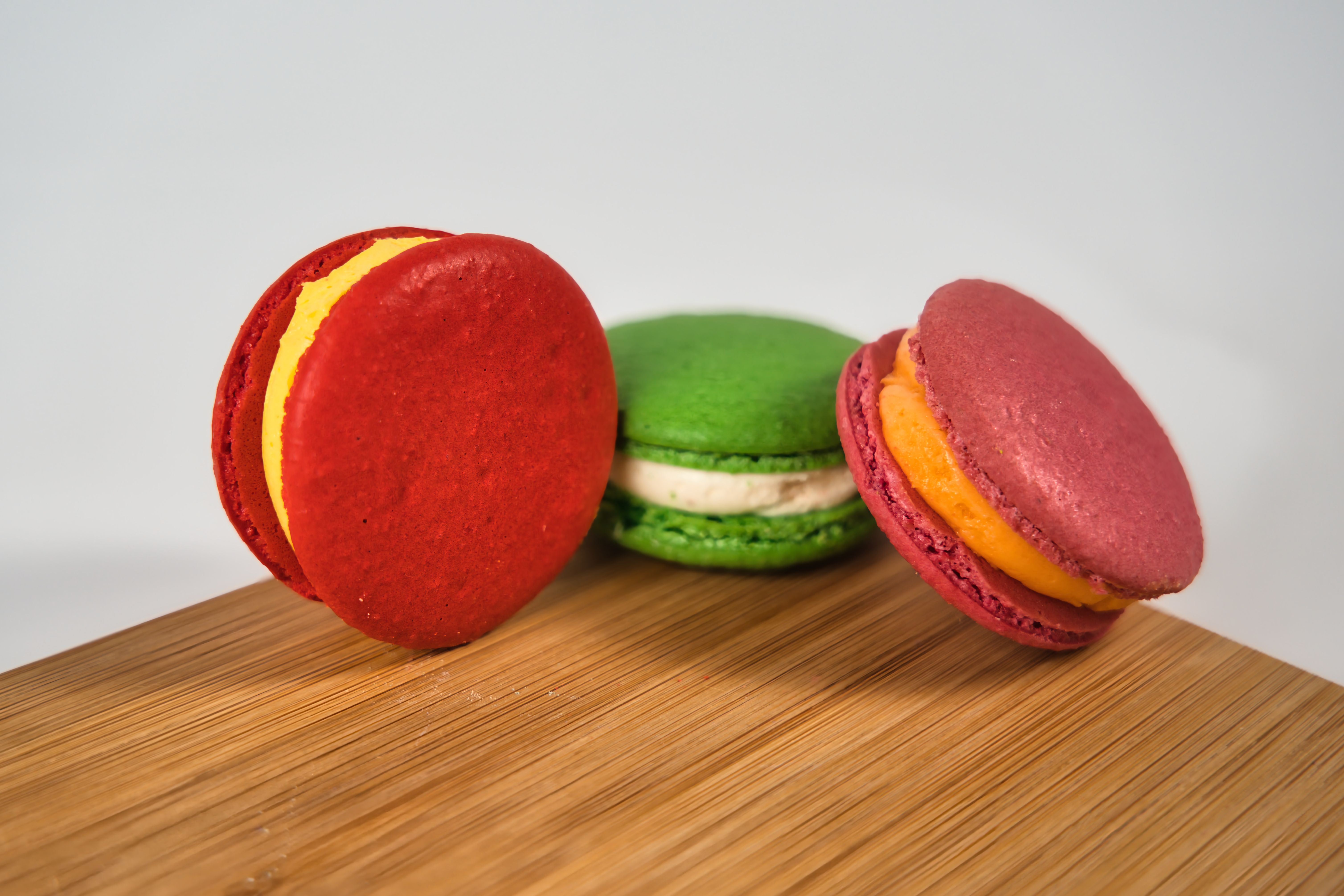 Colourful French macarons arranged on a wooden surface showing varied pastel shells and visible feet.