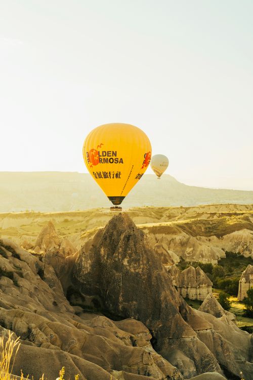 Free Scenic view of hot air balloons soaring above the stunning rock formations of Cappadocia at sunrise. Stock Photo