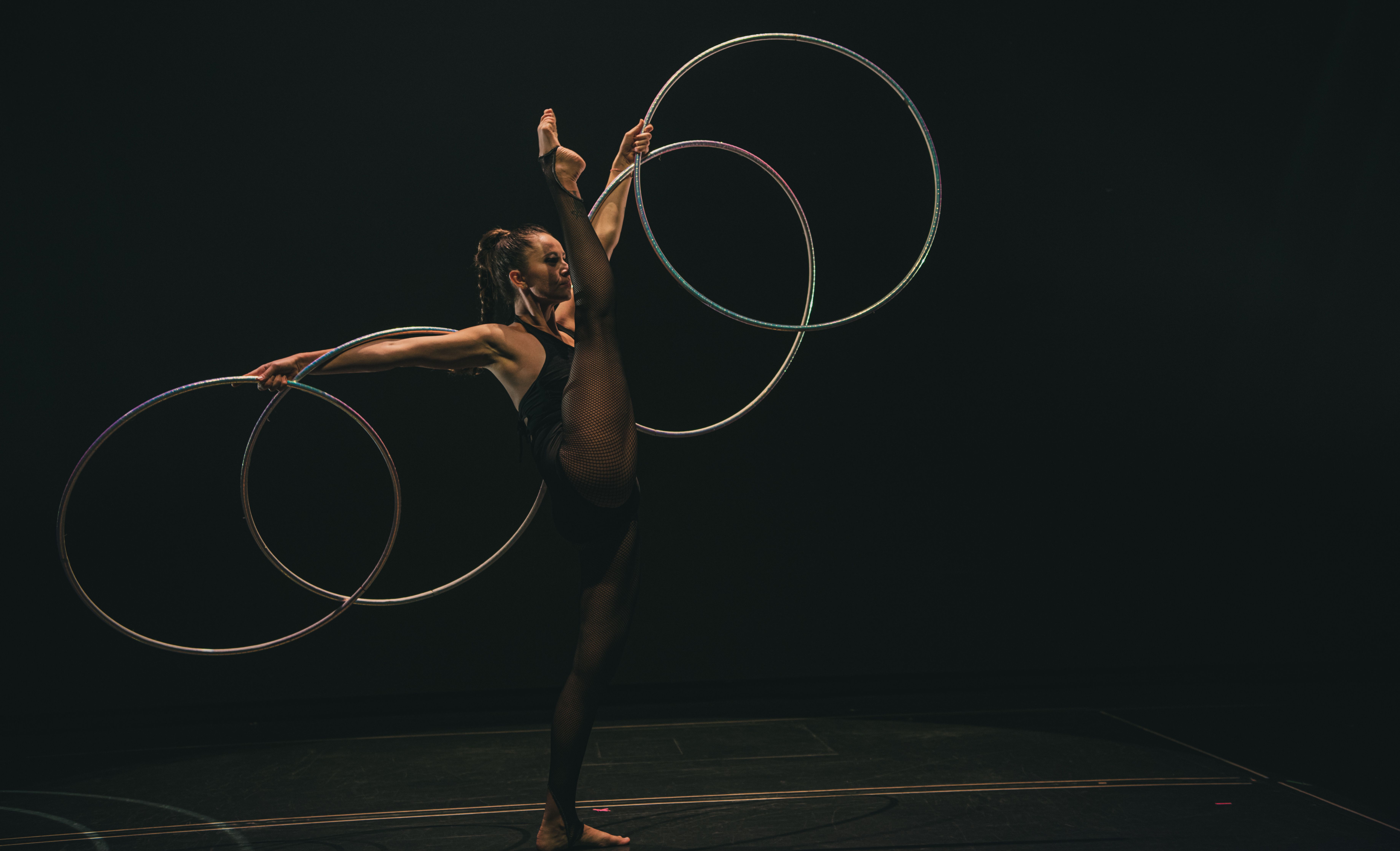 A talented acrobat executes a stunning performance with hoops under stage lighting.