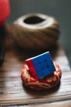 Blue Rubik's Cube placed on a red and gold decorative cushion indoors.