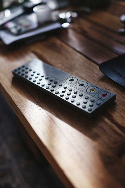 A close-up of a TV remote on a wooden table with soft sunlight streaming in.