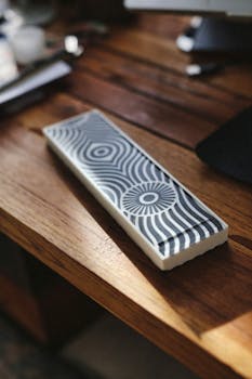 Decorative tile with geometric patterns placed on a sunlit wooden desk.