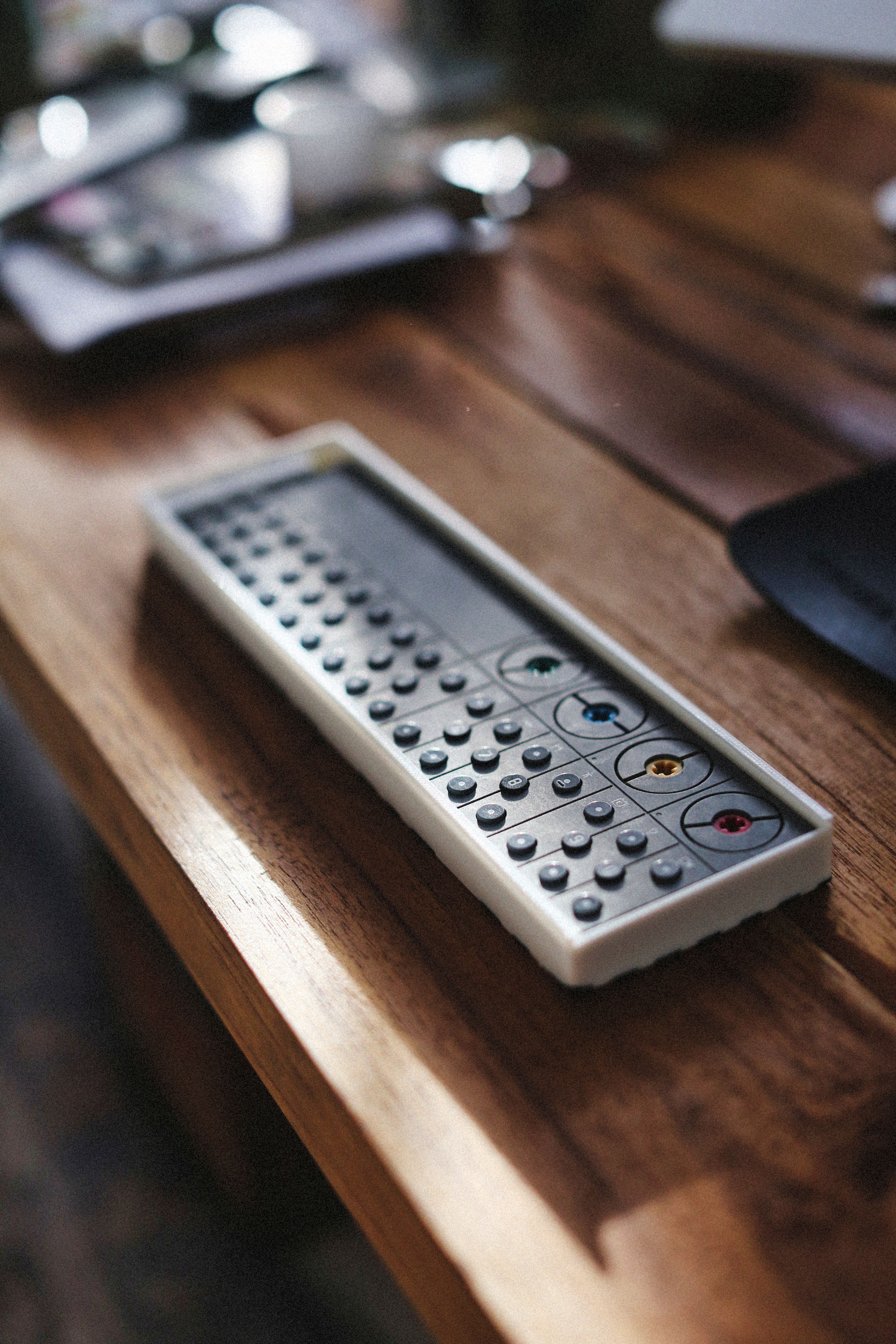 A compact and stylish synthesizer placed on a wooden table in natural light, showcasing its sleek design.