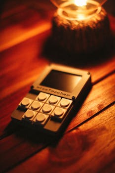 A vintage calculator resting on a wooden table illuminated by warm lamp light.
