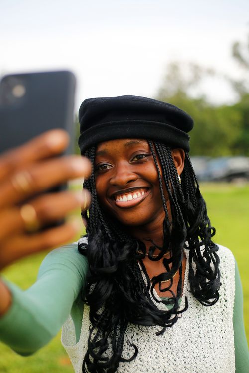 Free Smiling young woman in Abuja capturing a selfie with a phone, showcasing joy and technology. Stock Photo
