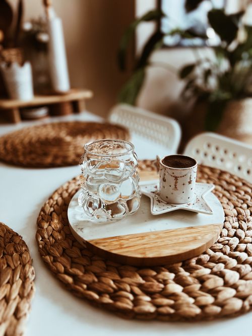 Free Beautifully arranged table with a coffee cup and glass on woven placemats, creating a warm atmosphere. Stock Photo