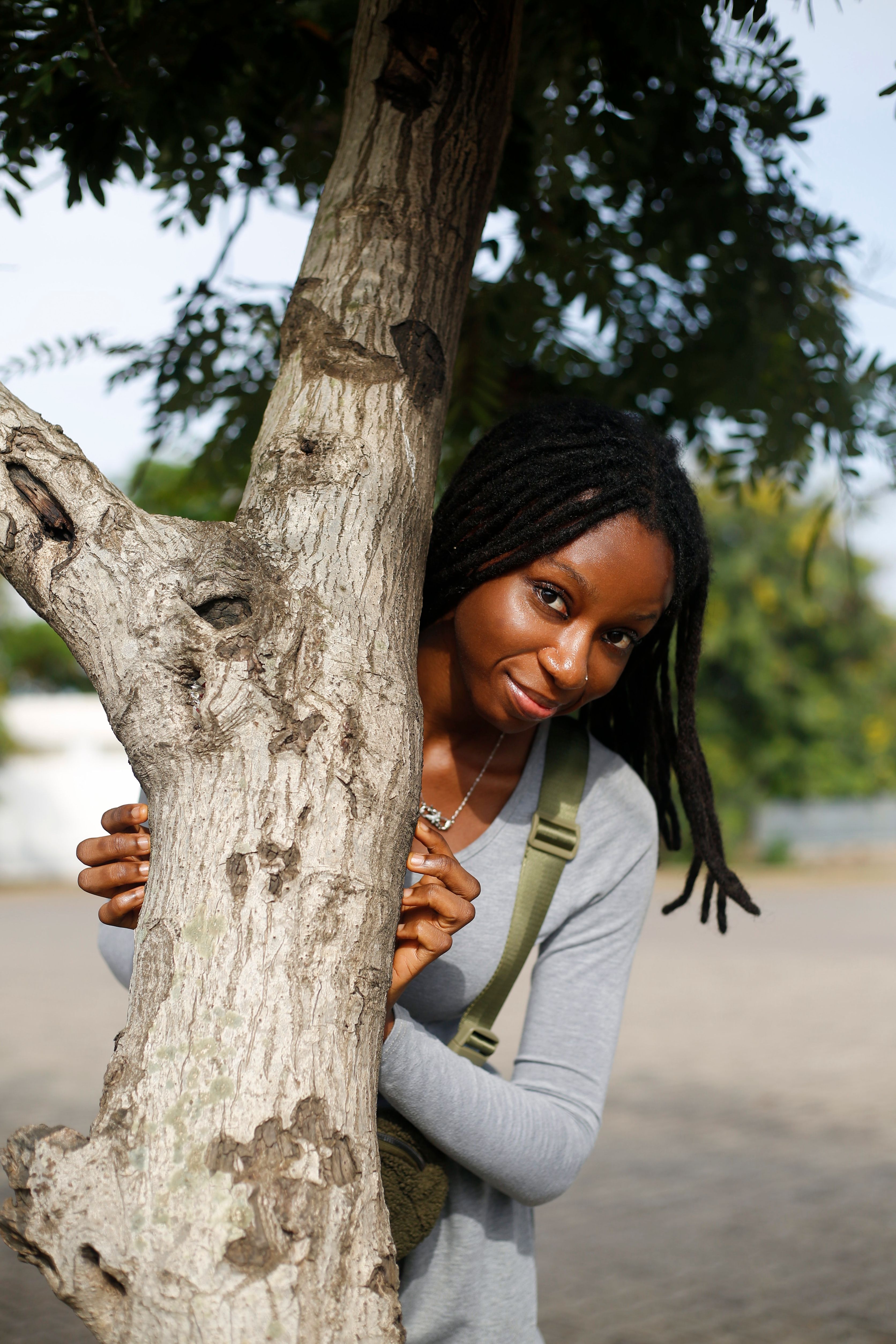 Smiling Woman Peeking from Behind Tree in Abuja · Free Stock Photo