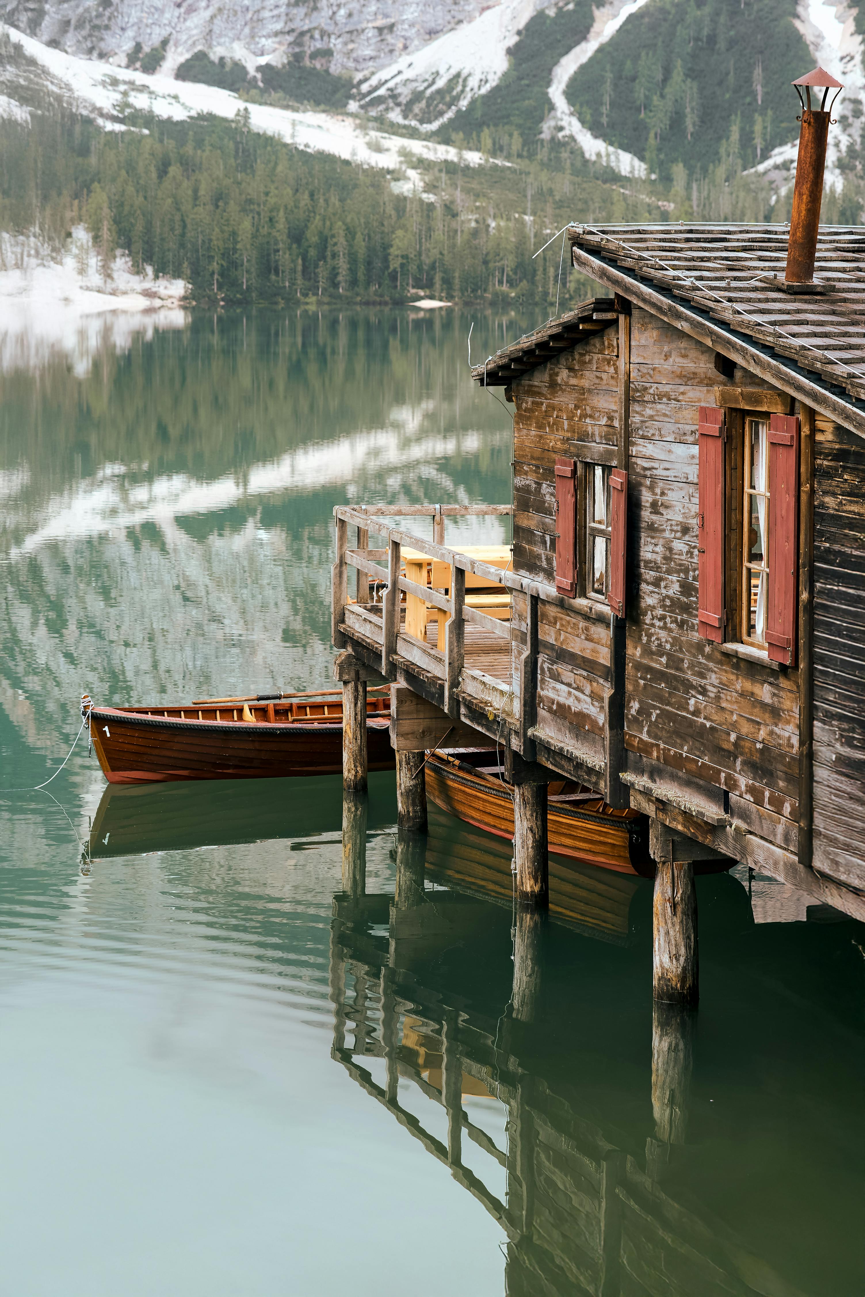 Tranquil lakeside cabin with vintage boats and mountain view.