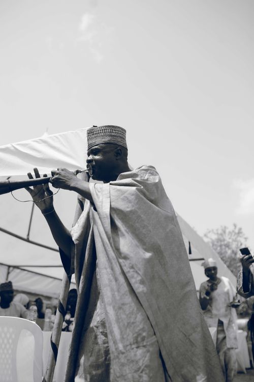 Free Black and white image of a traditional musician playing an instrument at an outdoor event. Stock Photo