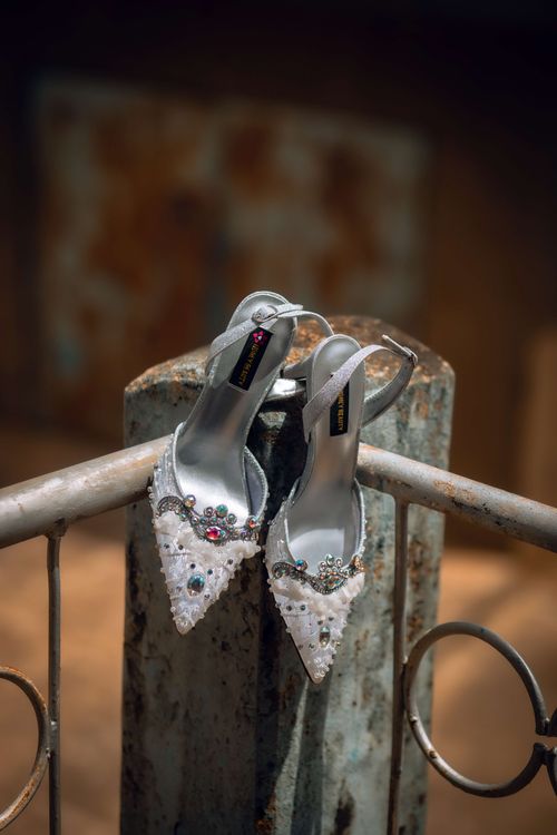 Free Pair of elegant bejeweled high heels displayed on a vintage railing, showcasing intricate craftsmanship. Stock Photo
