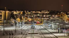 夜间，一座被雪覆盖的火车站亮起灯光，展现了城市的建筑与交通