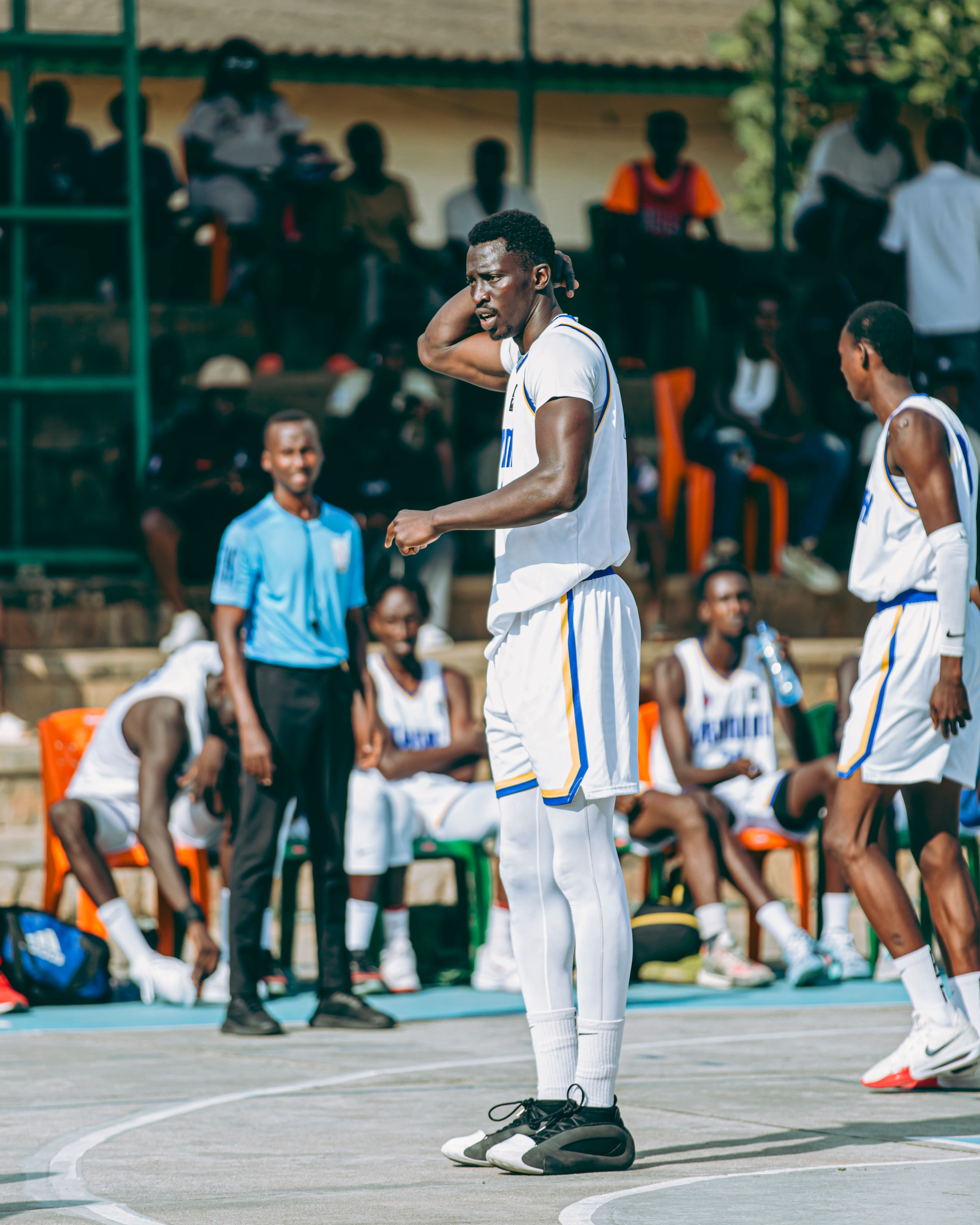 Basketball players and referee during an outdoor game under bright sunlight.