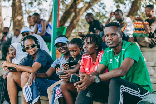 Free A diverse group of people enjoying a sunny day at an outdoor sports event, relaxing in the stands. Stock Photo