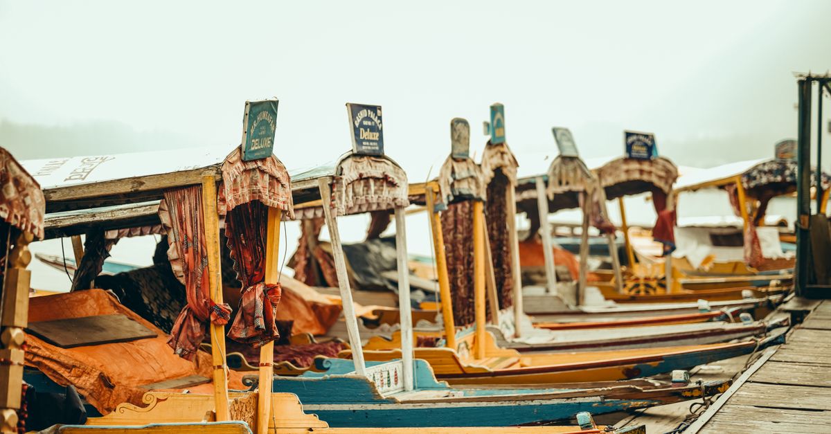 Traditional shikaras on a serene lake reflecting Kashmir heritage