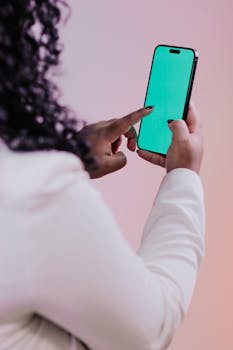 Closeup of a woman using a smartphone with a green screen, suitable for mockups.