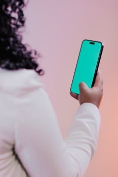 Adult holding a smartphone with a blank green screen, perfect for mockups.