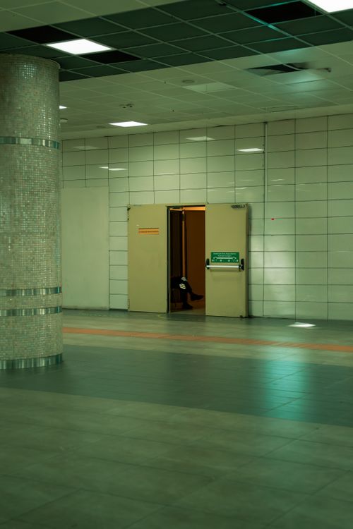 Free A quiet indoor hallway featuring an emergency exit door with a safety sign. Stock Photo