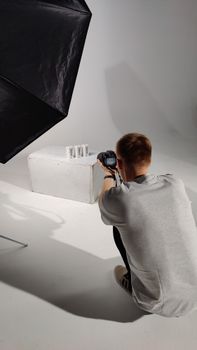 A photographer setting up for a product photoshoot in a professional studio environment.