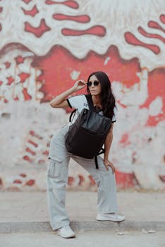 Fashionable woman in casual outfit posing confidently against a colorful graffiti wall.