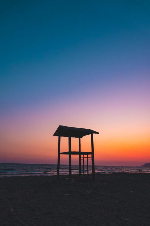 Free Beautiful sunset framing a silhouette of a lifeguard tower on Muğla's coast. Stock Photo