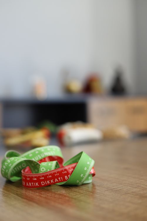 Free A vibrant measuring tape lies on a wooden table with blurred background items. Stock Photo