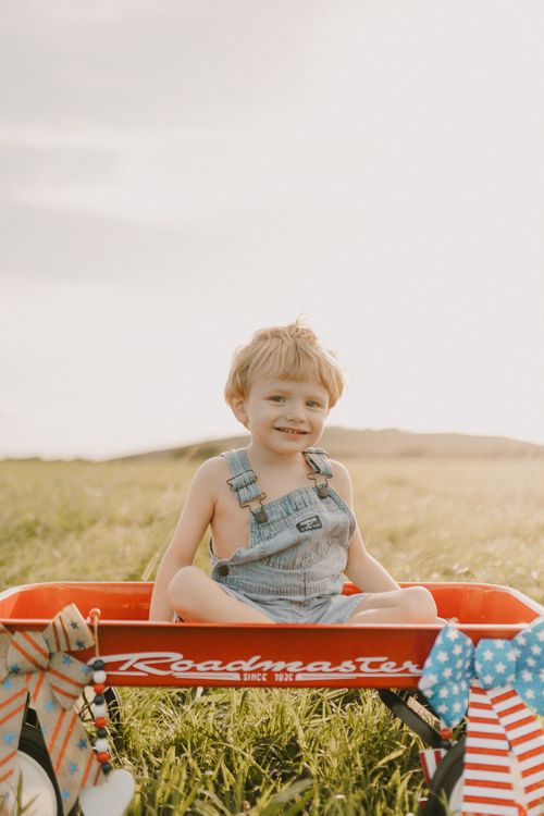 Free Happy child sitting in a red wagon outdoors, celebrating summer in West Palm Beach. Stock Photo