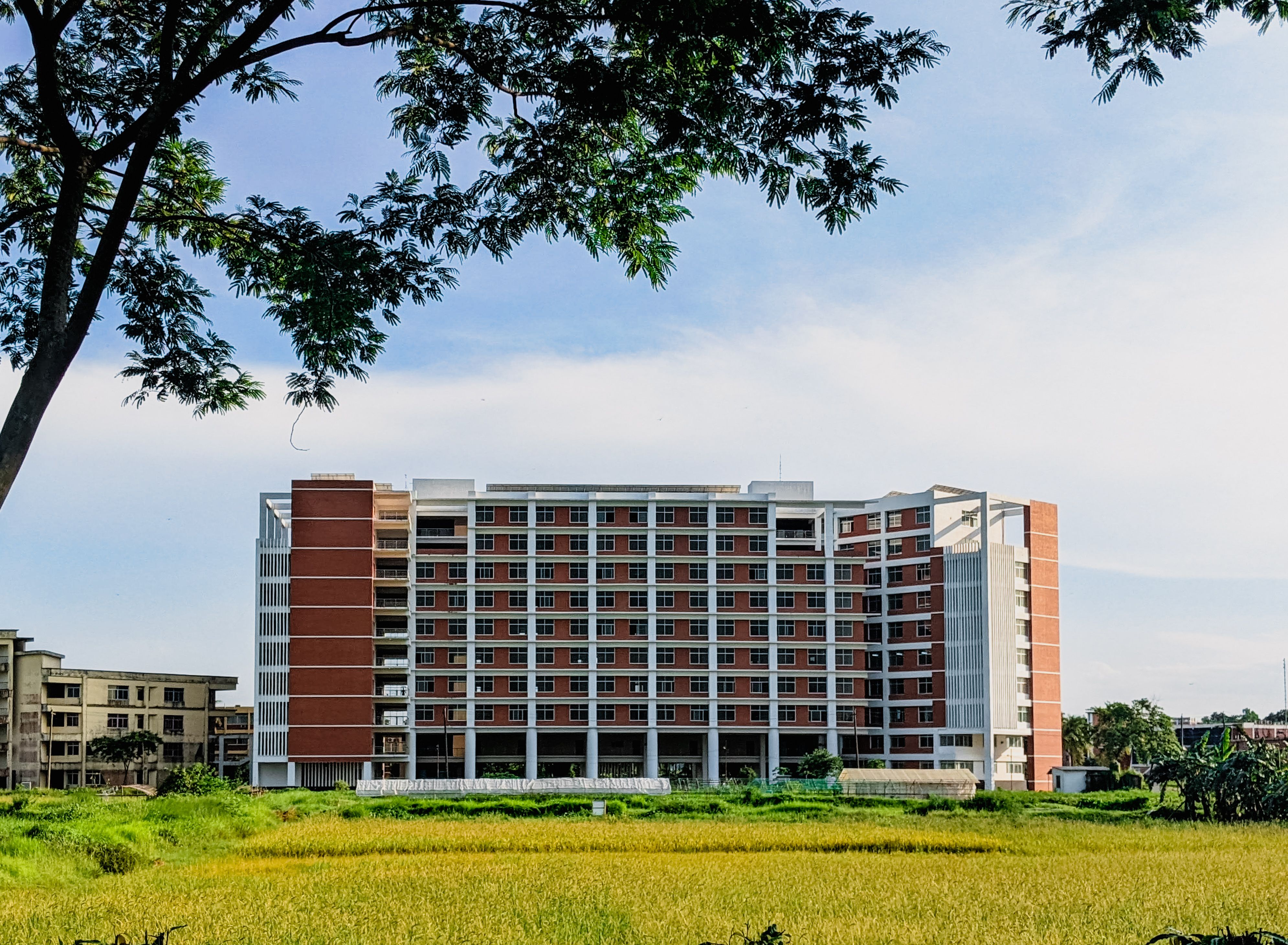 A modern apartment building surrounded by lush greenery and clear skies in a serene outdoor location.