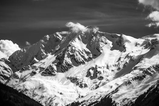 Striking black and white photograph of a snow-covered mountain peak showcasing dramatic textures and high contrast.