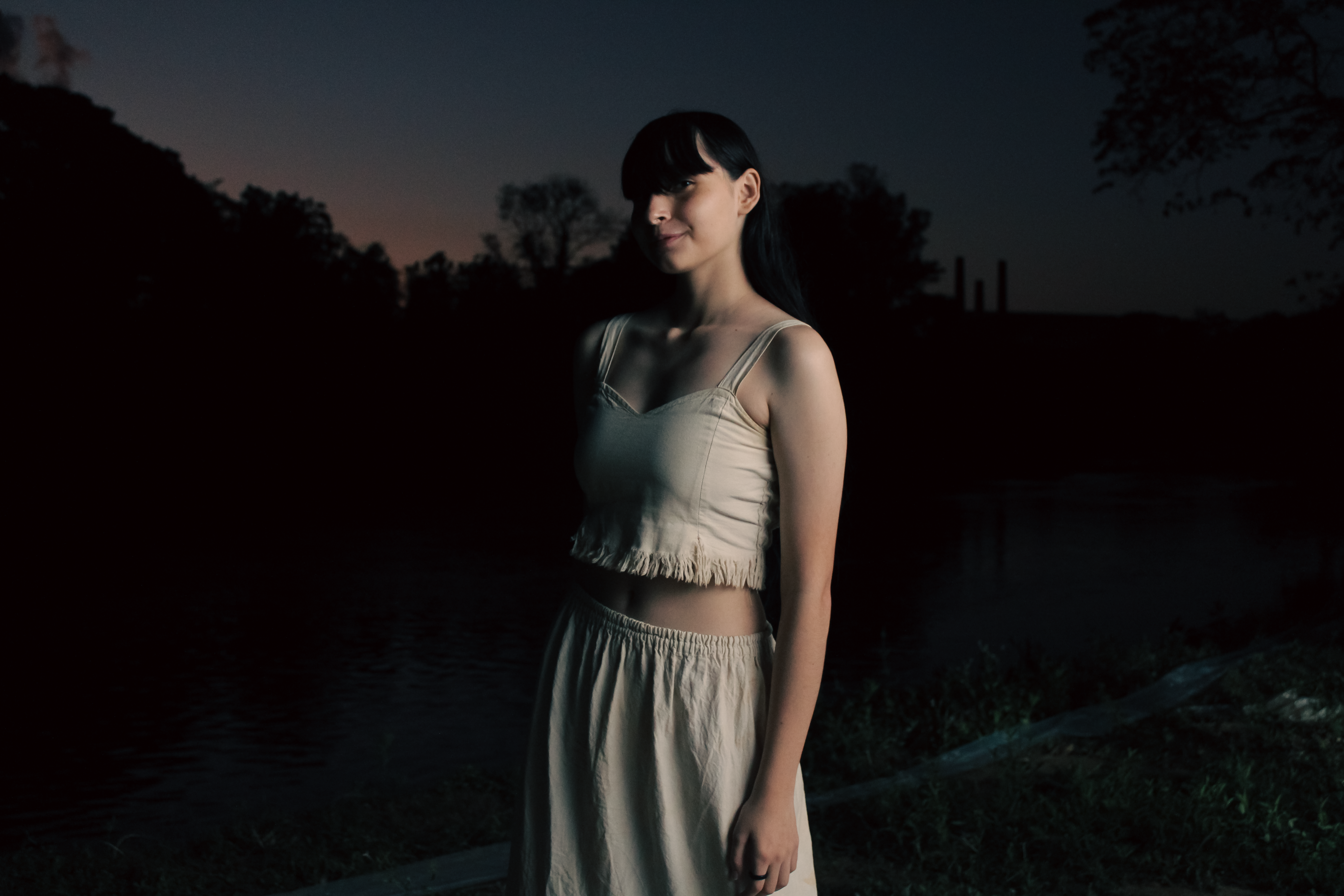 A serene portrait of a woman outdoors at twilight, exuding calm and elegance.