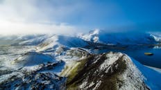 蔚蓝天空下，白雪覆盖的山脉与平静的湖泊构成了一幅迷人的鸟瞰图