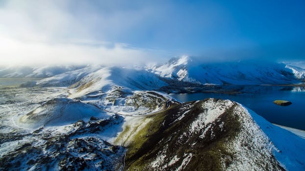蔚蓝天空下，白雪覆盖的山脉与平静的湖泊构成了一幅迷人的鸟瞰图