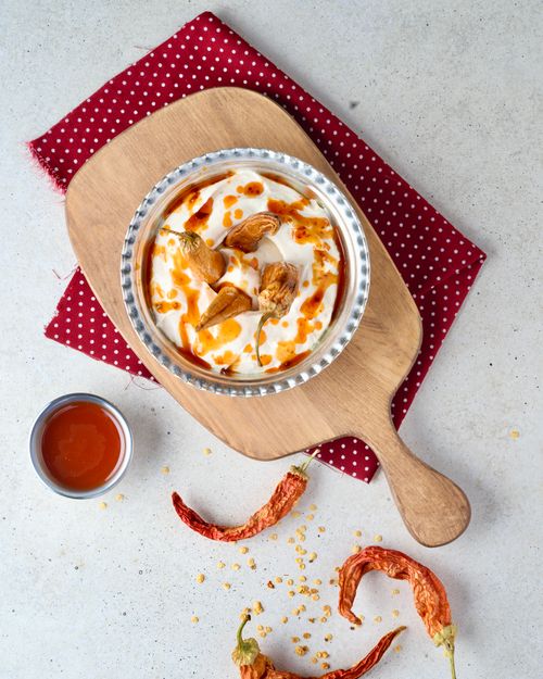 Free A delicious spicy yogurt dish served on a wooden board, garnished with chili oil. Stock Photo