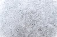 白色背景上，冰霜图案的详细特写创造出抽象的冬季纹理