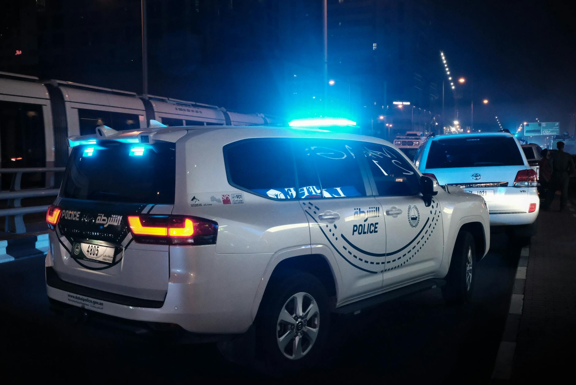 Night scene of police patrol cars with flashing lights in Dubai, UAE showcasing law enforcement presence.